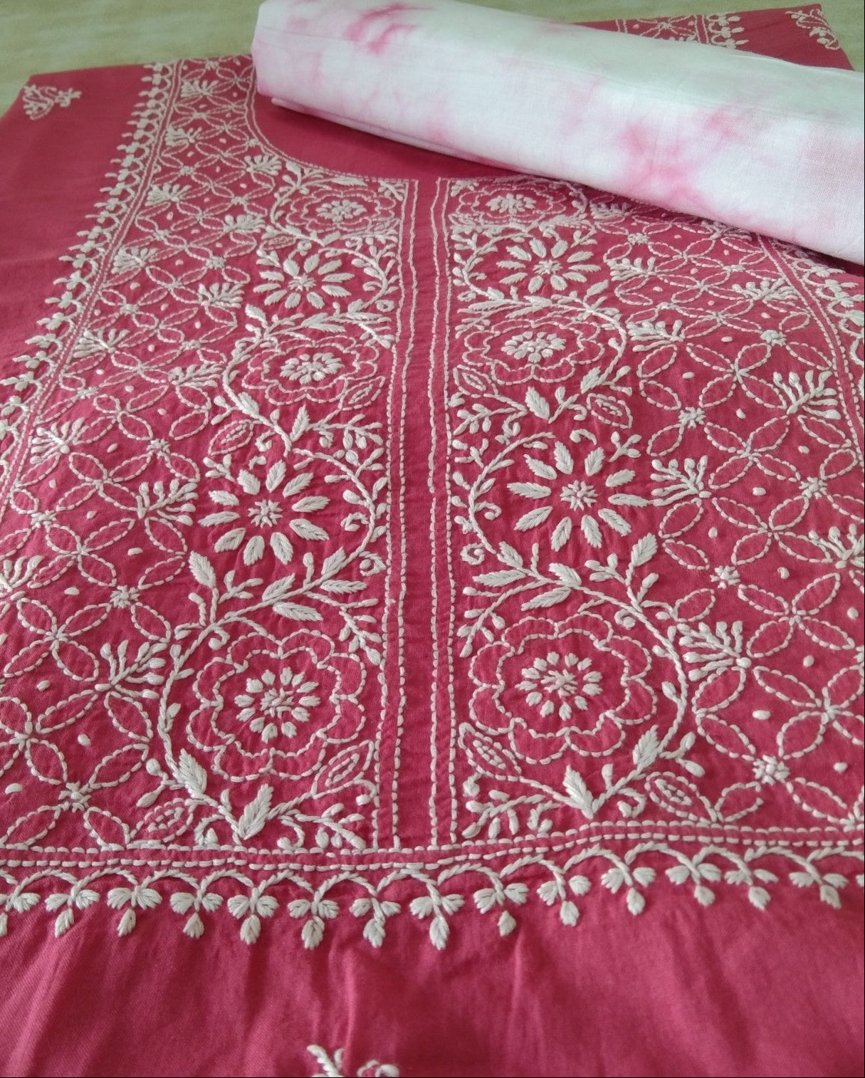 Pink fabric with white floral patterns on a wooden surface